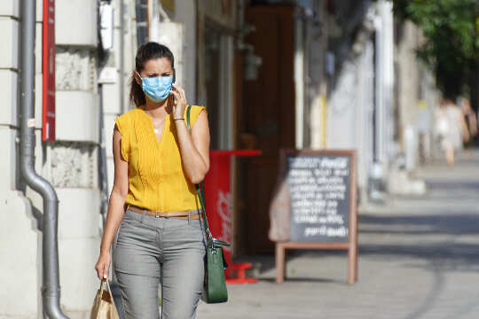 Here Are Some Things Might Make You A Disease Super-spreader woman walking down the street wearing a mask and touching her face
