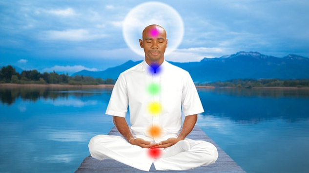 a man sitting in meditation with chakras lit up