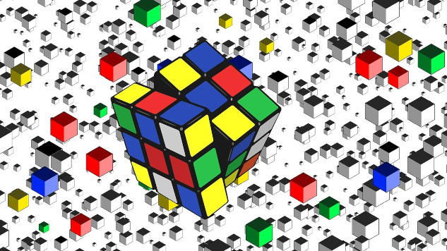 a rubik cube in progress, with a whole bunch of single cubes spread in chaos all around it.