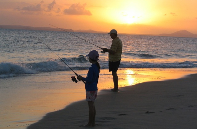 father and son fishing on the shore at sunrise