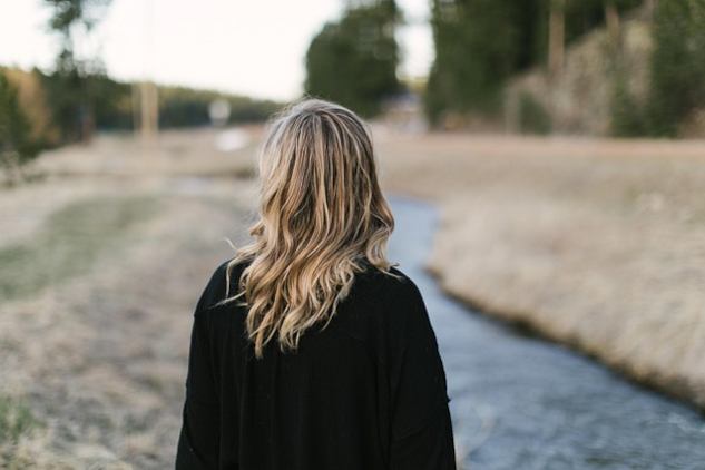 A woman seen from the back looking at the path in front of her. Image by brittywing from Pixabay.