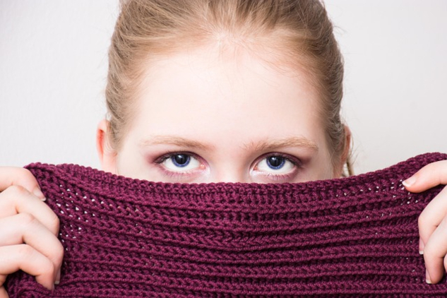 Young woman hiding half of her face behind a knitted cloth. Image by Anemone123 from Pixabay.&nbsp;